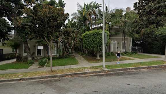 A person is walking on the sidewalk in front of a house.
