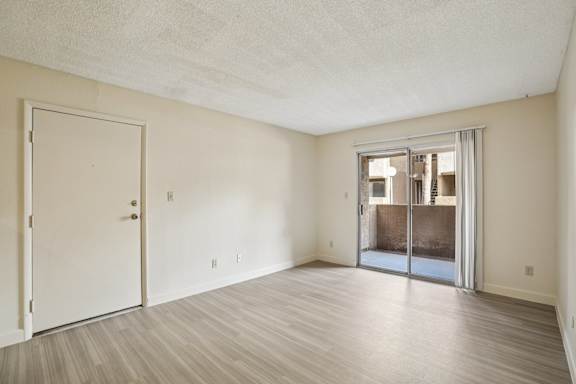 A room with a white door and a sliding glass door leading to a balcony.
