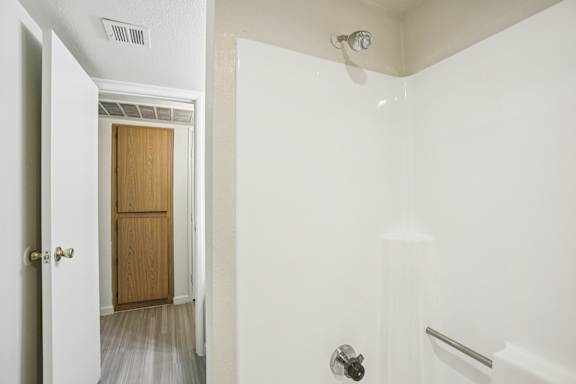 A white bathroom with a door and a shower.