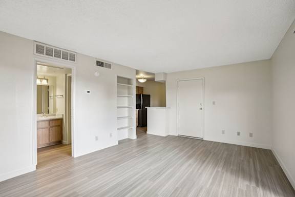 A large empty room with wood flooring and white walls.