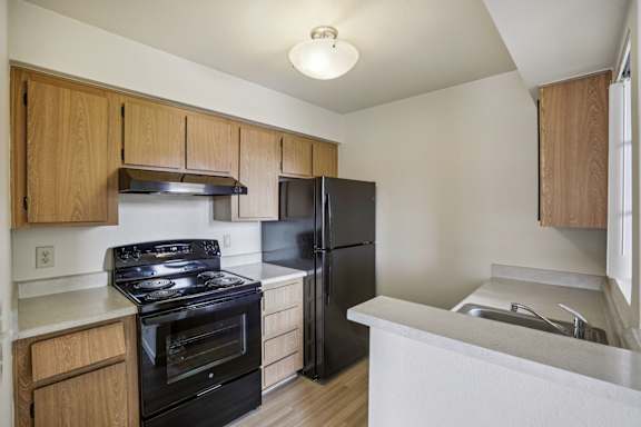 A kitchen with black appliances and wooden cabinets.