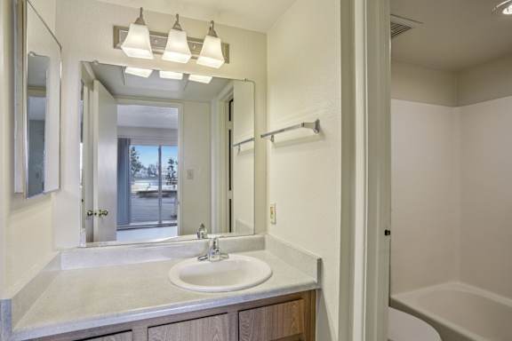 A bathroom with a sink, mirror, and tub.