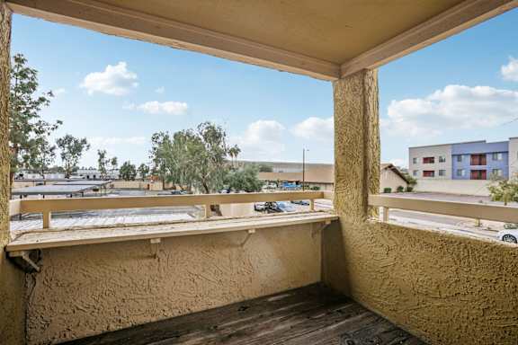 A balcony with a view of a parking lot and buildings.