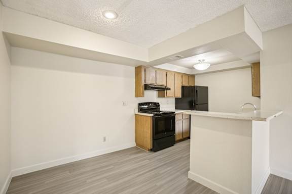 A kitchen area with a black fridge, stove, and microwave.