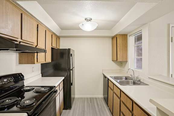 A kitchen with black appliances and wooden cabinets.