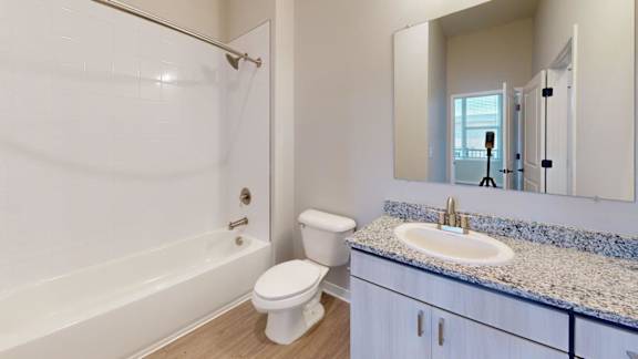 A white toilet sits next to a white bathtub in a bathroom.