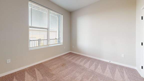 A room with a carpeted floor and a window with blinds.