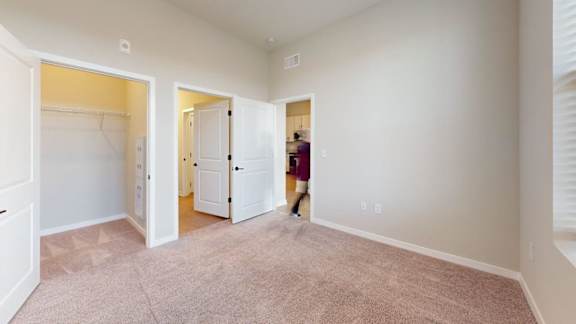 A woman is walking through a hallway with white walls and carpeted floors.