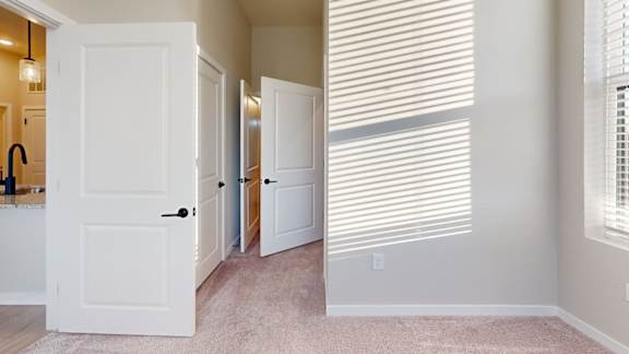A white door is open in a room with a carpeted floor.