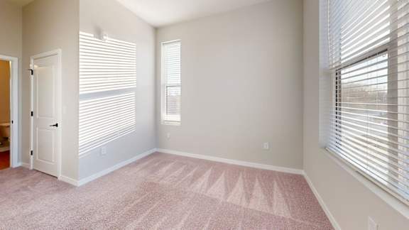 A room with a carpeted floor and a window with blinds.