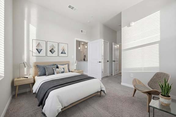 A bedroom with a bed, chair, and potted plant.