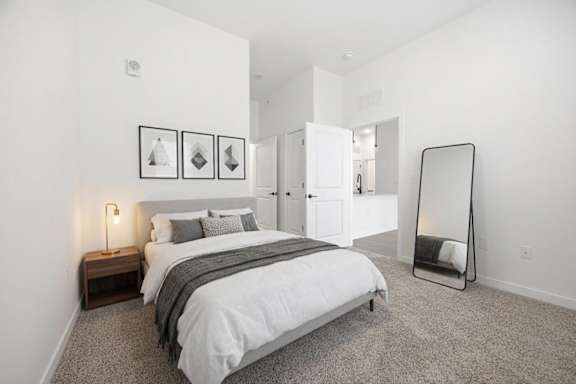 A bedroom with a bed, nightstand, and a mirror.