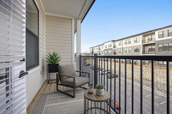 A balcony with a chair, table, and potted plant.