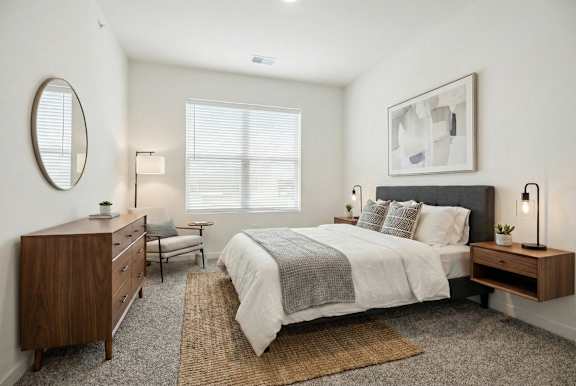 A bedroom with a bed, nightstand, and chair.