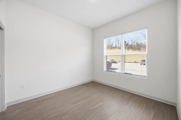 A room with a window showing a view of a parking lot.