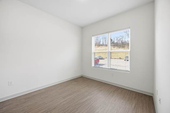 A room with a window showing a view of a field.