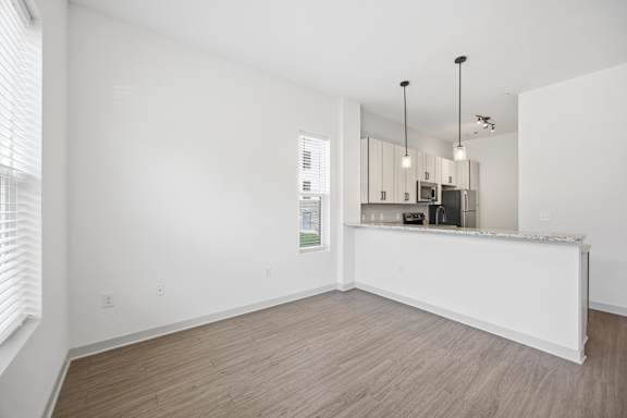 A spacious, empty room with a kitchenette in the background.