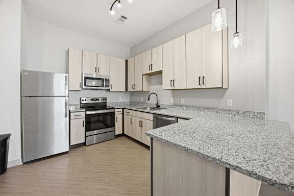 A kitchen with a granite counter top and stainless steel appliances.