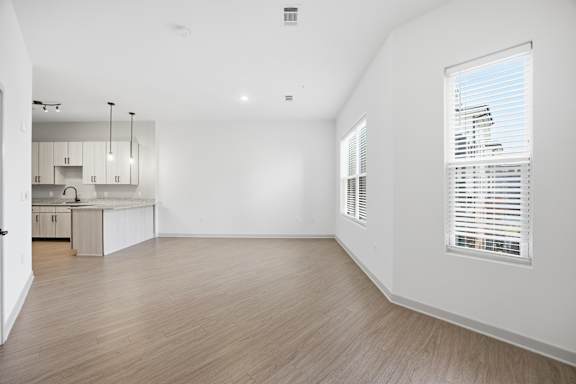 A spacious room with wooden flooring and white walls.