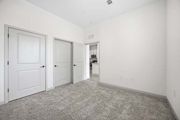 A room with three doors and a carpeted floor.