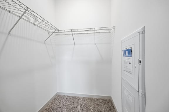 A white closet with a metal rack and a white door with a screen.