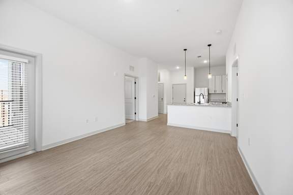A spacious room with wooden flooring and white walls.