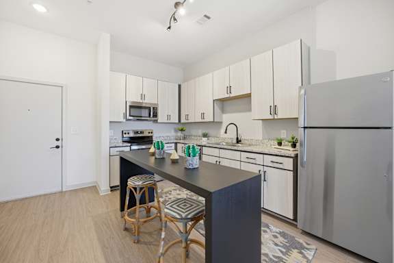 A kitchen with white cabinets and a black island.