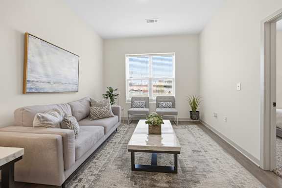 A living room with a couch, a coffee table, and a painting on the wall.