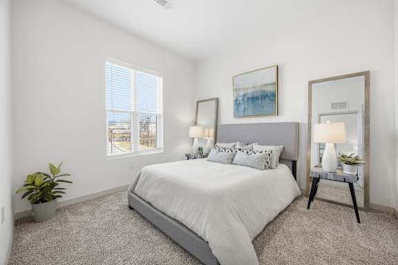 A bedroom with a large bed, a potted plant, and a painting on the wall.