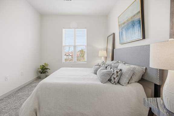 A bedroom with a large bed and a painting on the wall.