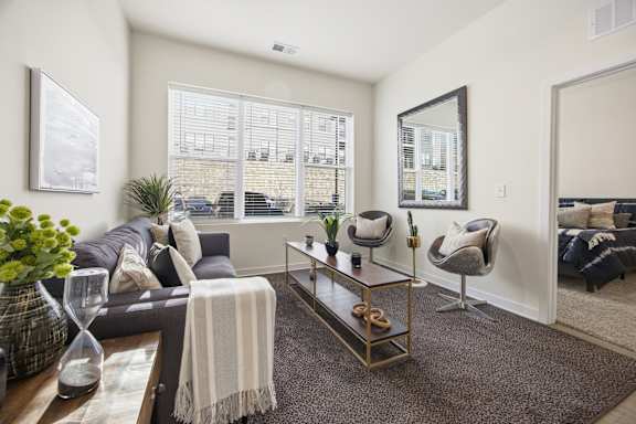 A living room with a grey couch, a coffee table, and a large window.