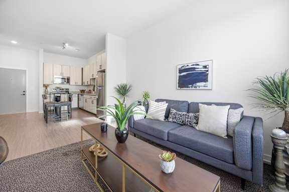 A living room with a blue couch and a painting on the wall.