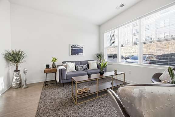 A living room with a grey couch, a coffee table, and a large window.