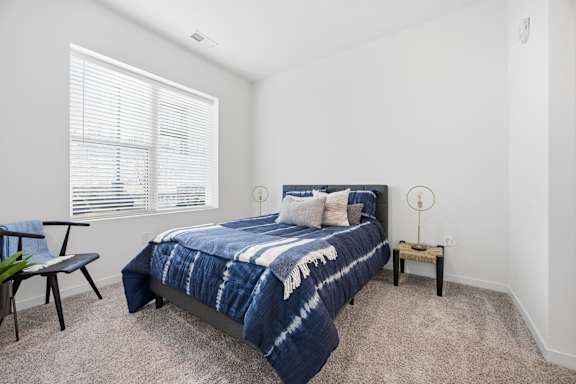 A bedroom with a bed, a chair, and a small table.