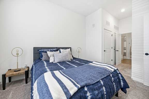 A bed with a blue and white comforter is in the center of the image.