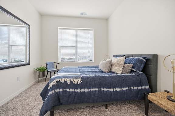 A bedroom with a bed, a chair, and a window.