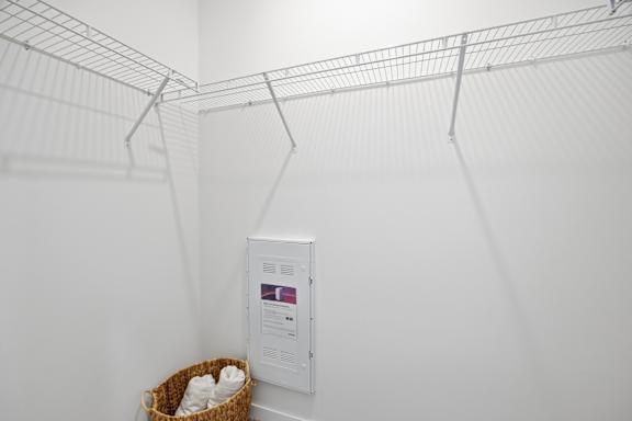 A wire shelving unit with a basket and a box on the wall.