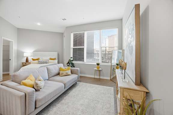 A living room with a grey couch and yellow pillows.
