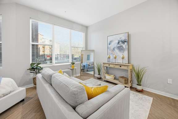 A living room with a grey couch and a painting on the wall.