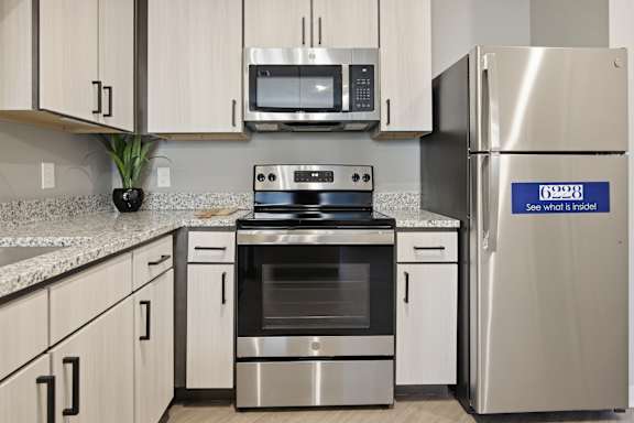 A modern kitchen with a stainless steel refrigerator that has a blue sticker on it.