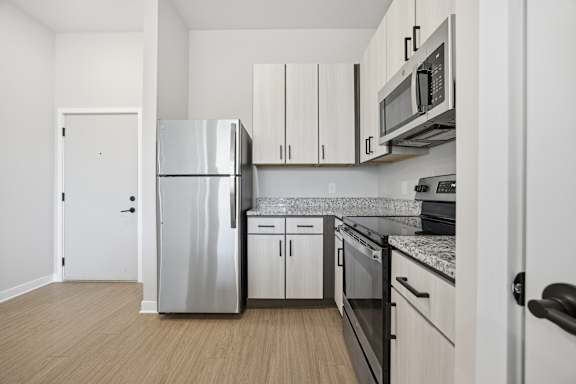 A kitchen with a refrigerator, microwave, oven, and cabinets.