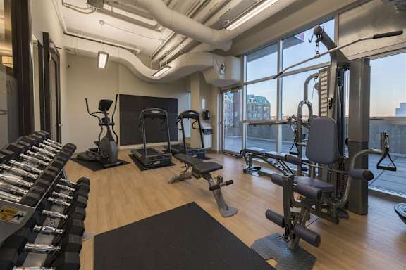 A gym with a variety of equipment including treadmills, weights, and exercise machines.