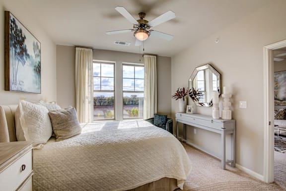 A bedroom with a large bed and a ceiling fan.