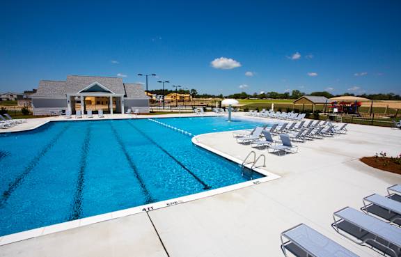 A pool in front of a building with palm trees.