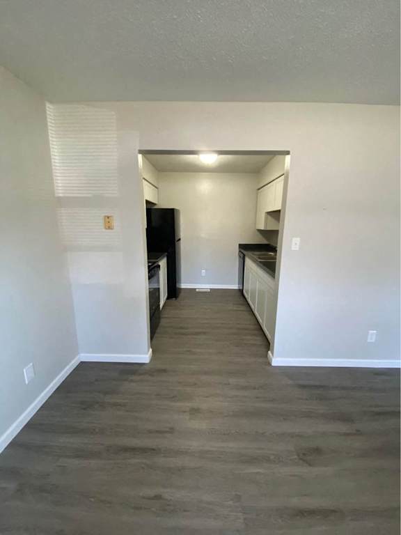 a renovated living room and kitchen with white walls and wood floors