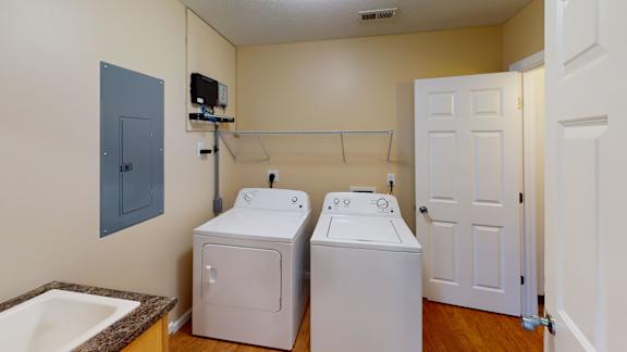 a laundry room with two washers and dryers and a door to a bathroom
