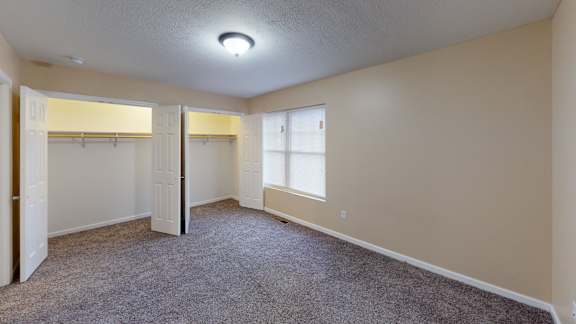 an empty room with a closet and a window