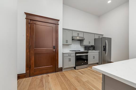 A kitchen with a wooden door and a white counter.