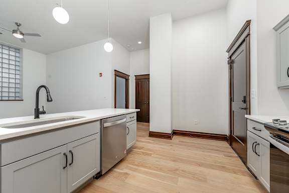 A kitchen with white cabinets and a wooden floor.