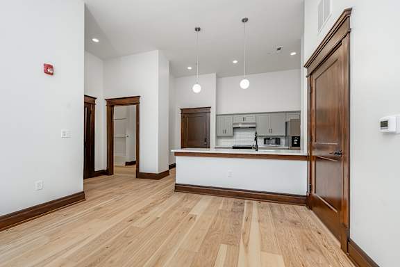 A kitchen with white walls and wooden floors.